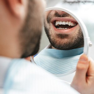 Dental patient smiling at reflection in handheld mirror