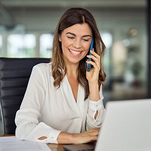 Woman smiling while talking on phone in office