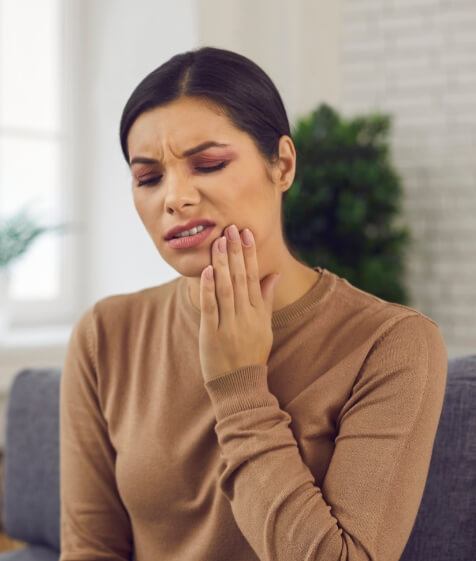 Woman holding her cheek in pain before restorative dentistry