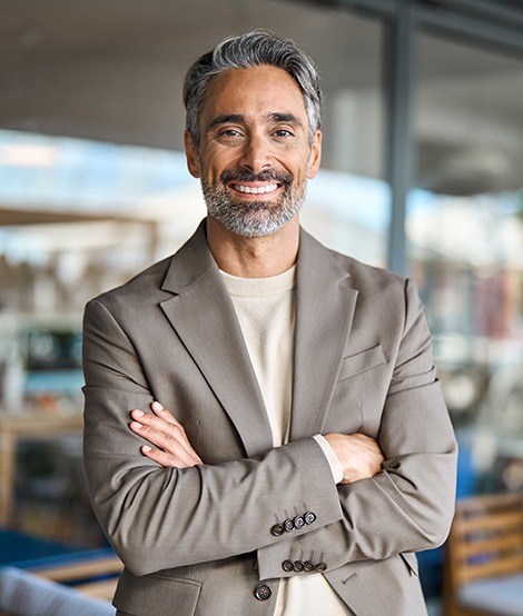 A middle-aged businessman smiling with dental crowns in Medford