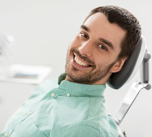 A smiling man sitting in a dental chair