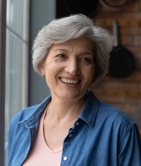 Woman in a denim shirt smiling with dentures in Medford