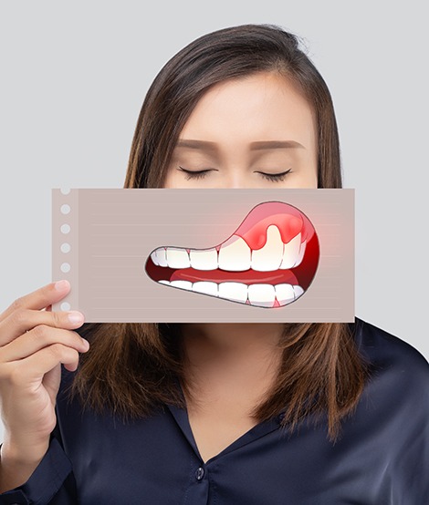 Woman in dark blue shirt holding image of gum disease over her mouth while closing her eyes
