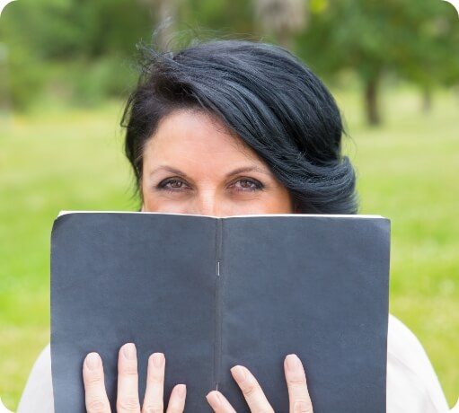 Woman covering her smile with a little black book