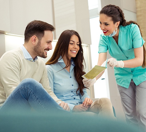 Dental assistant showing smiling couple form