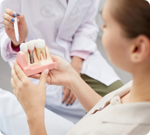 Dentist and patient looking at a model of a dental implant