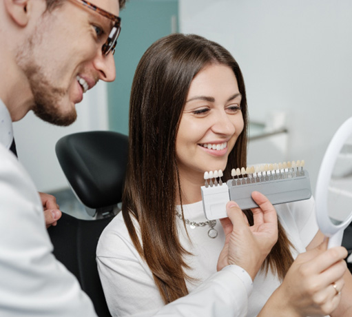 Dentist showing patient different shades of veneers