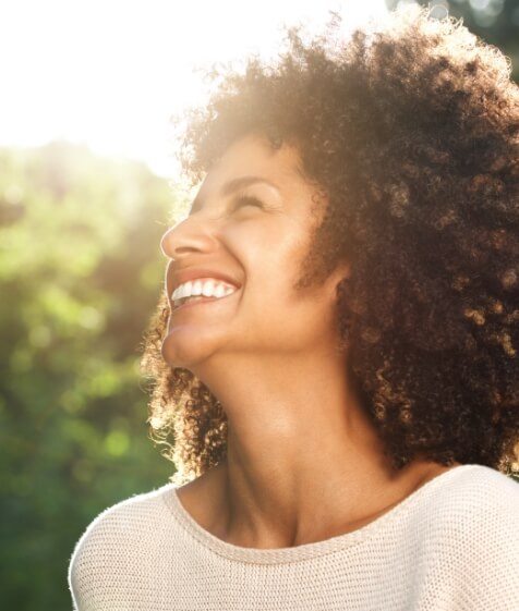 Woman smiling in the sun with veneers in Medford