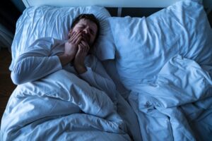 Man laying down on bed with a toothache