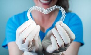 gloved hands holding clear aligners